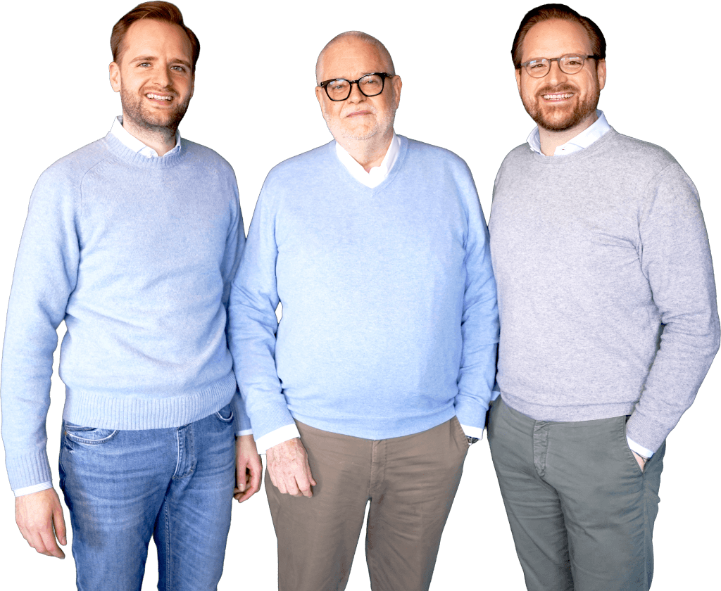 Drei lächelnde Männer, die das Team von Voigt dental repräsentieren, stehen nebeneinander und blicken freundlich in die Kamera.